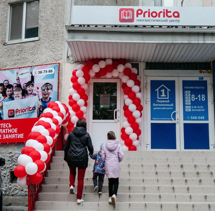 Семья поднимается на крыльцо филиала Priorita под аркой из шаров